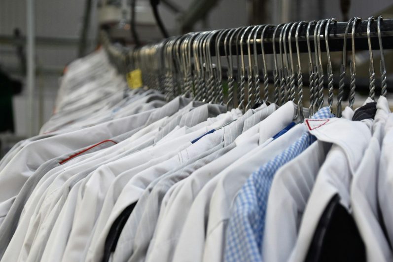 Hängende Hemden in verschiedenen Farben und Mustern auf Kleiderbügeln.