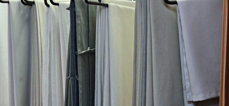 Mehrere graue Vorhänge hängen an Kleiderbügeln.
